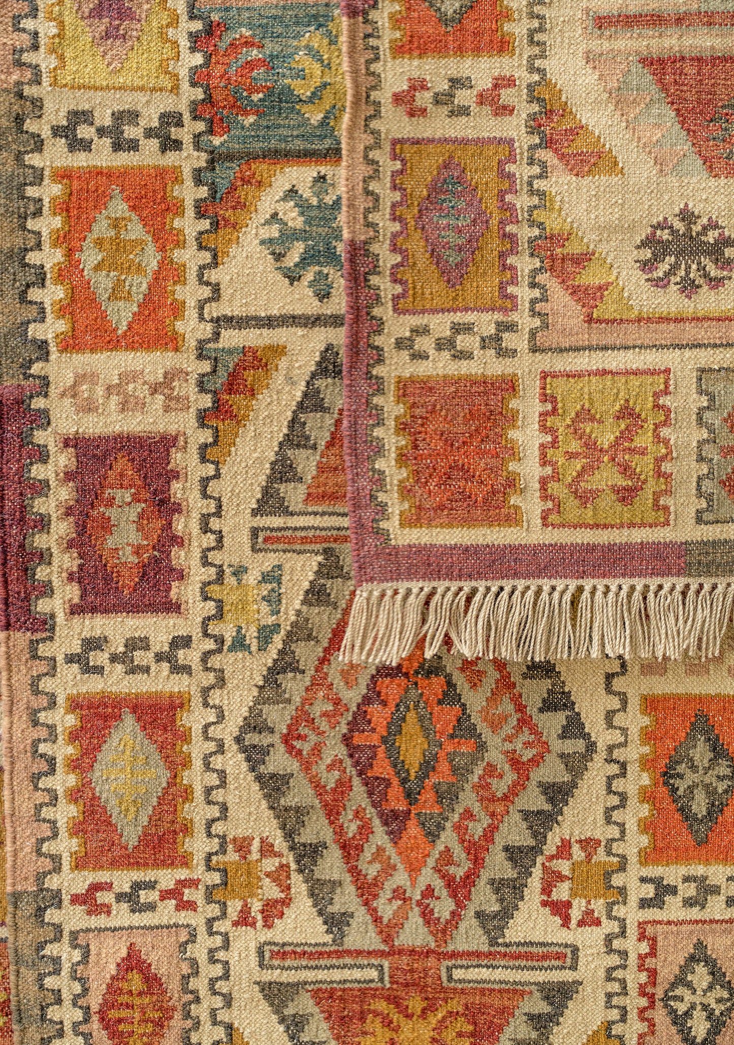 Close-up of a patterned rug with geometric designs in red, orange, and beige.