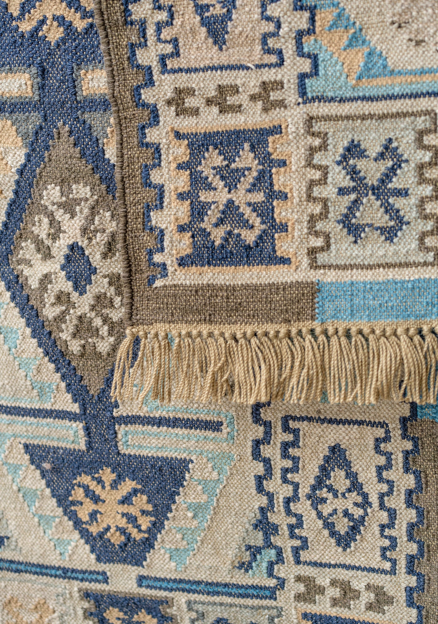 Close-up of a patterned rug with geometric designs in blue, beige, and brown.