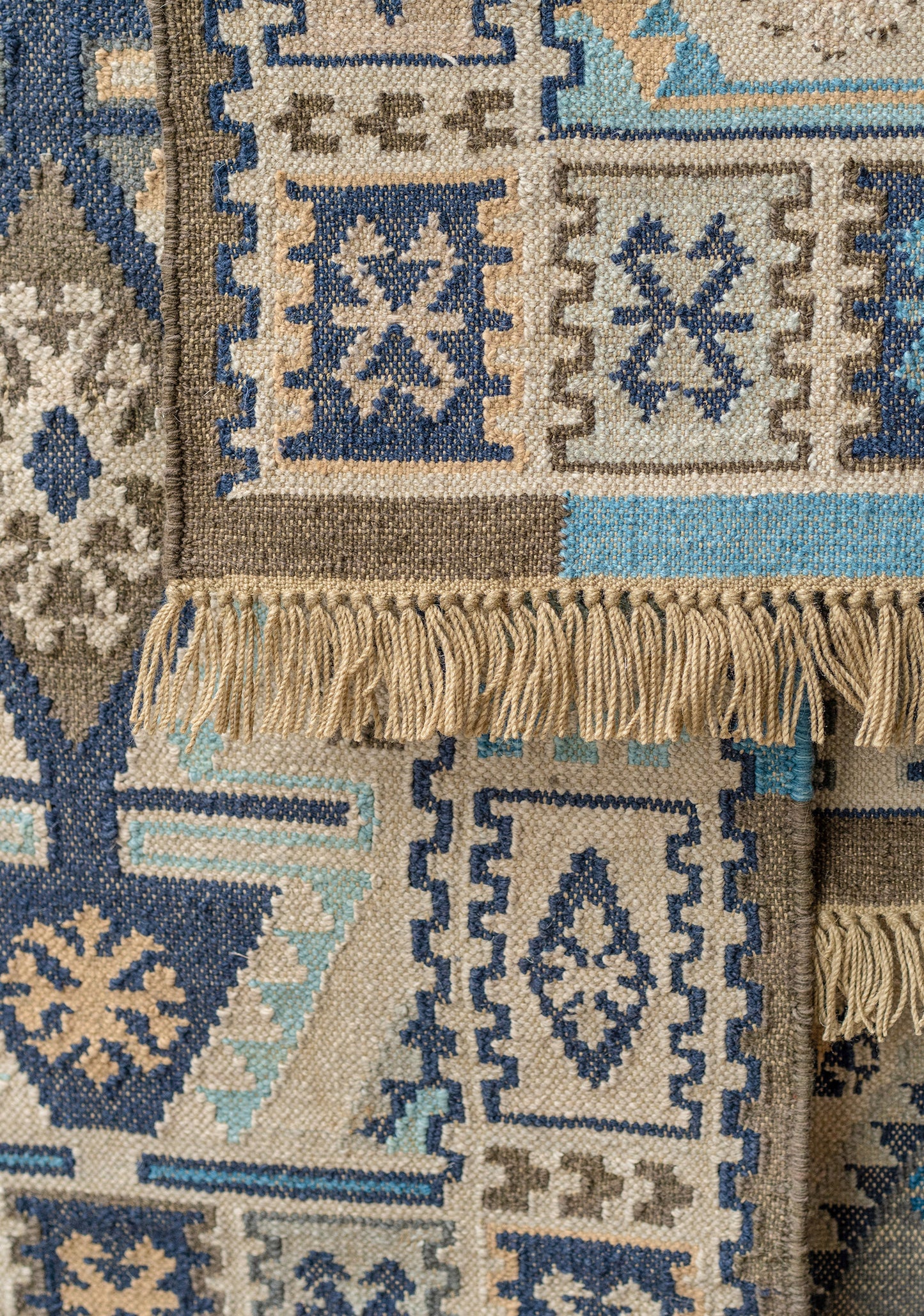 Close-up of a patterned rug with geometric designs in blue, beige, and brown.