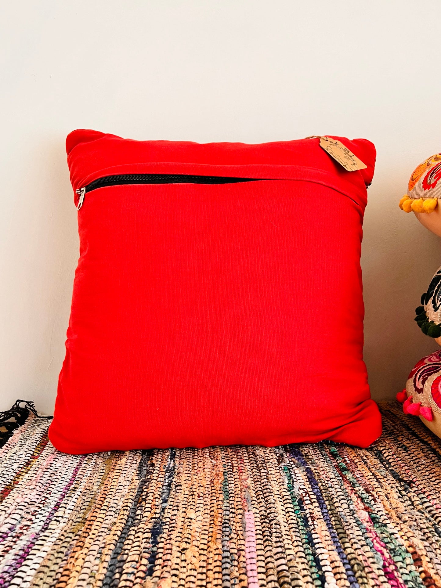 Red pillow with a zipper on a textured surface handmade fair trade