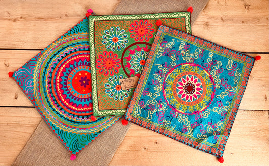vibrant silk style fabric cushion covers with hand embroidered boho hippie chic pattern designs in three vibrant colours with Pom Pom edge detail, handmade fair trade & ethical