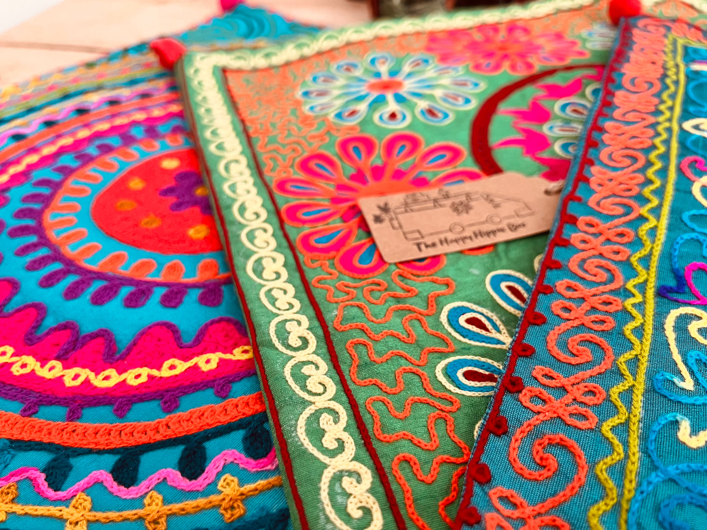 vibrant silk style fabric cushion covers with hand embroidered boho hippie chic pattern designs in three vibrant colours with Pom Pom edge detail, handmade fair trade & ethical