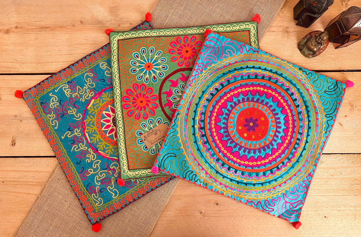 vibrant silk style fabric cushion covers with hand embroidered boho hippie chic pattern designs in three vibrant colours with Pom Pom edge detail, handmade fair trade & ethical