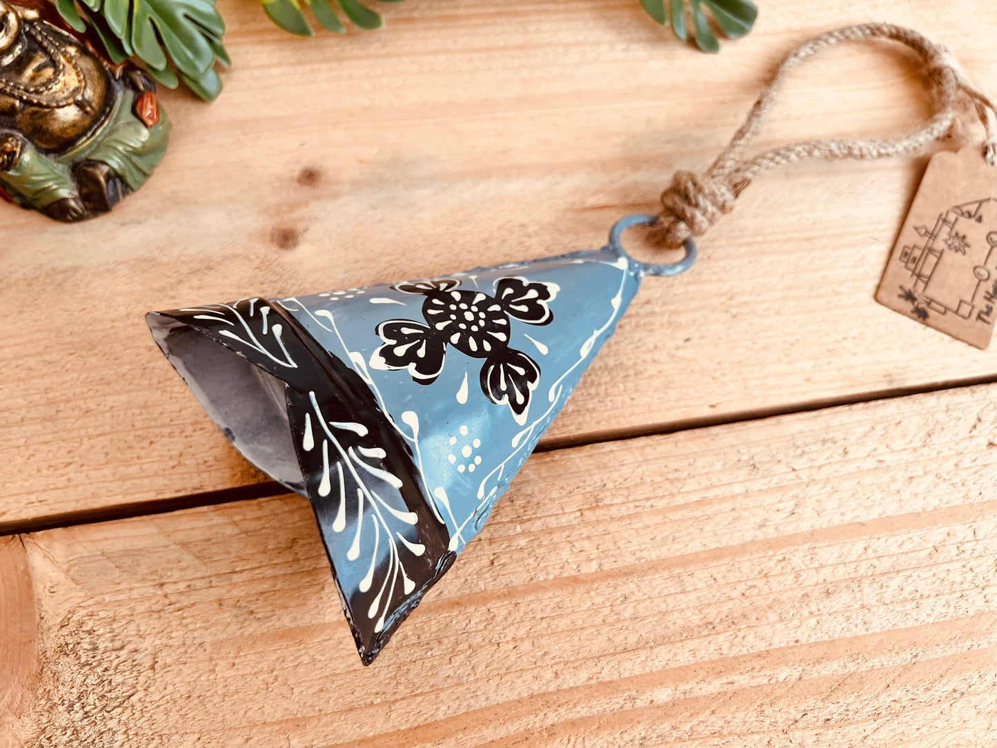 Hand-painted large recycled metal bell in light grey, feather painted with black and white floral patterns, hanging on rustic jute twine. Handmade, fair trade hippie boho decor.