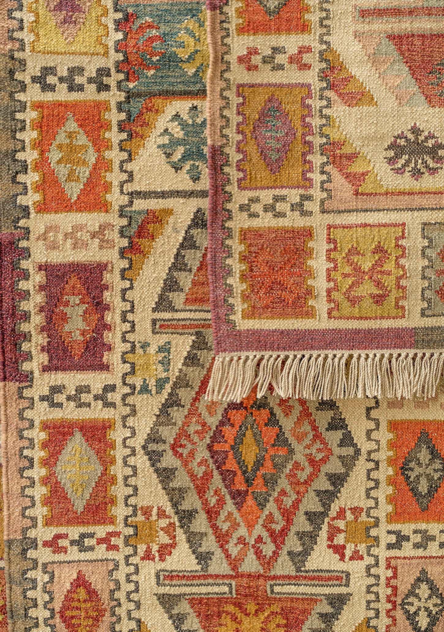 Close-up of a patterned rug with geometric designs in red, orange, and beige.