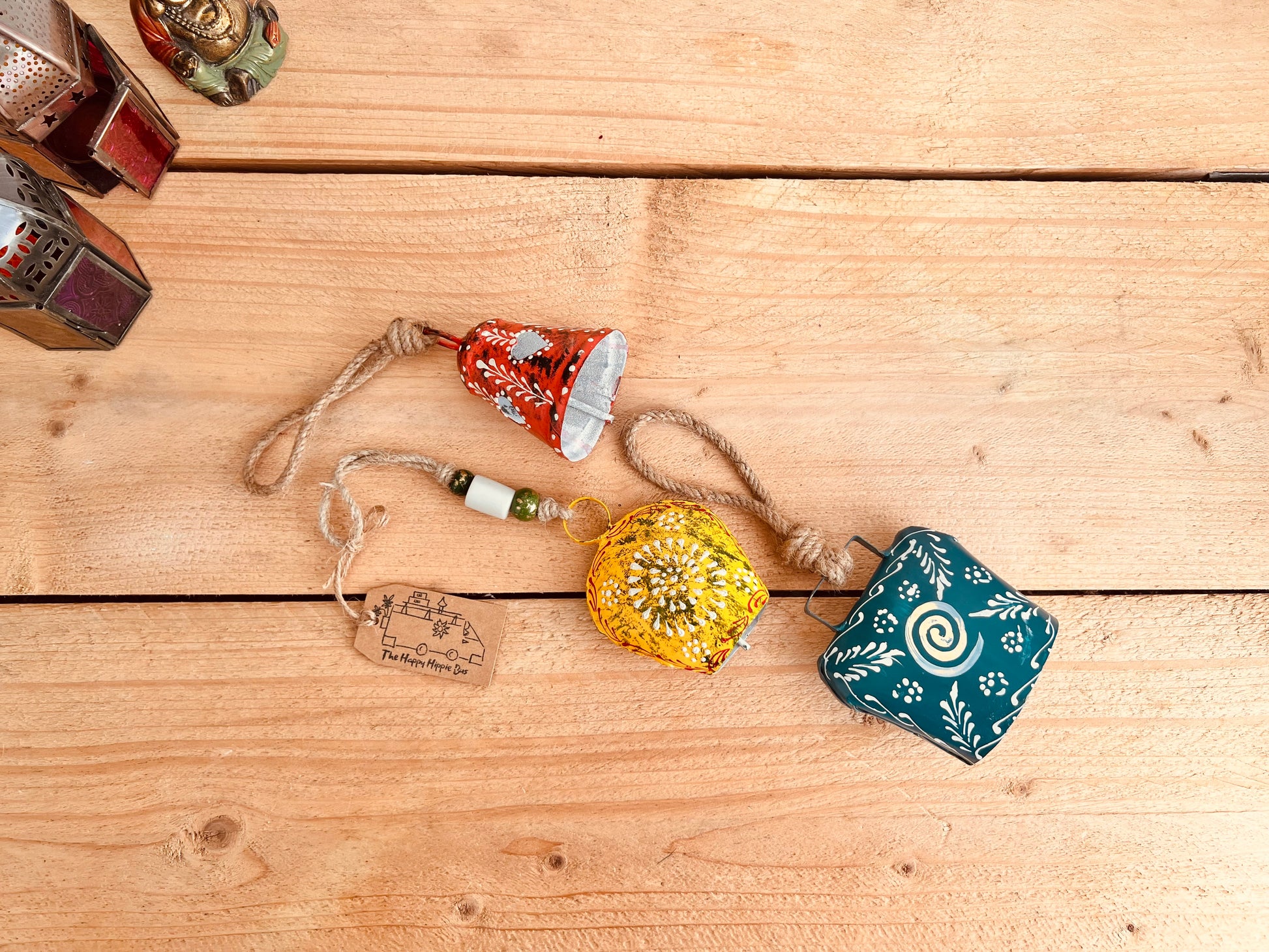 a set of three metal hand painted Indian hanging bells in three different sizes, jute twine hanging cow bell wind chimes in three mixed sizes, yellow, red & blue metal painted bells, handmade, fair trade & ethically sourced hippie boho home decor. 