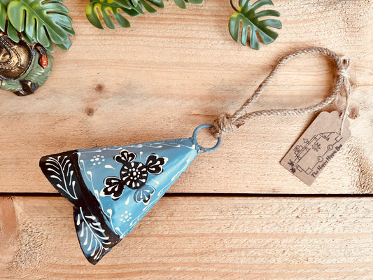 A hand-painted recycled metal bell in light grey with black and white floral patterns, hanging on rustic jute twine. Handmade, fair trade hippie boho decor.