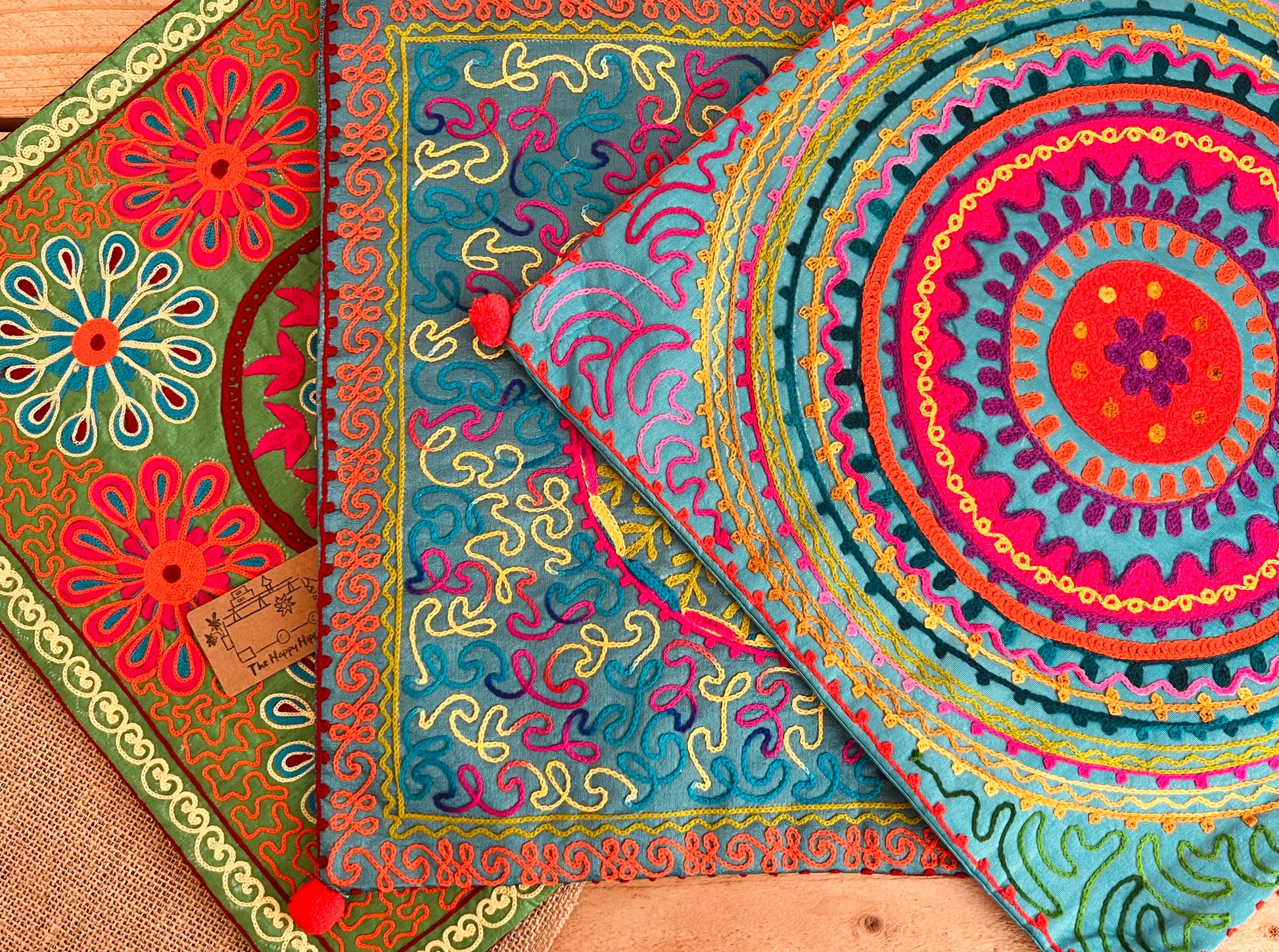vibrant silk style fabric cushion covers with hand embroidered boho hippie chic pattern designs in three vibrant colours with Pom Pom edge detail, handmade fair trade & ethical