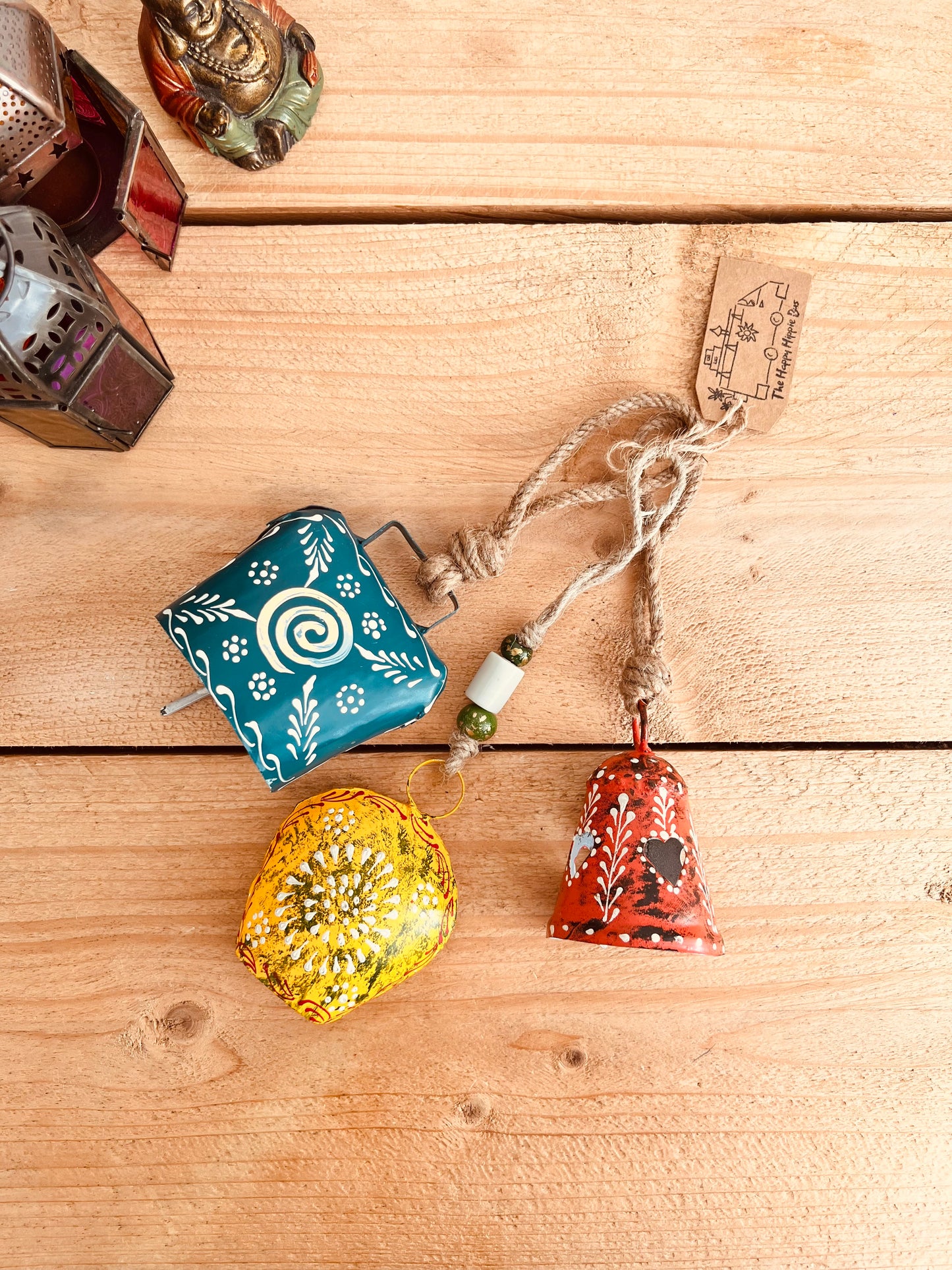 a set of three metal hand painted Indian hanging bells in three different sizes, jute twine hanging cow bell wind chimes in three mixed sizes, yellow, red & blue metal painted bells, handmade, fair trade & ethically sourced hippie boho home decor. 