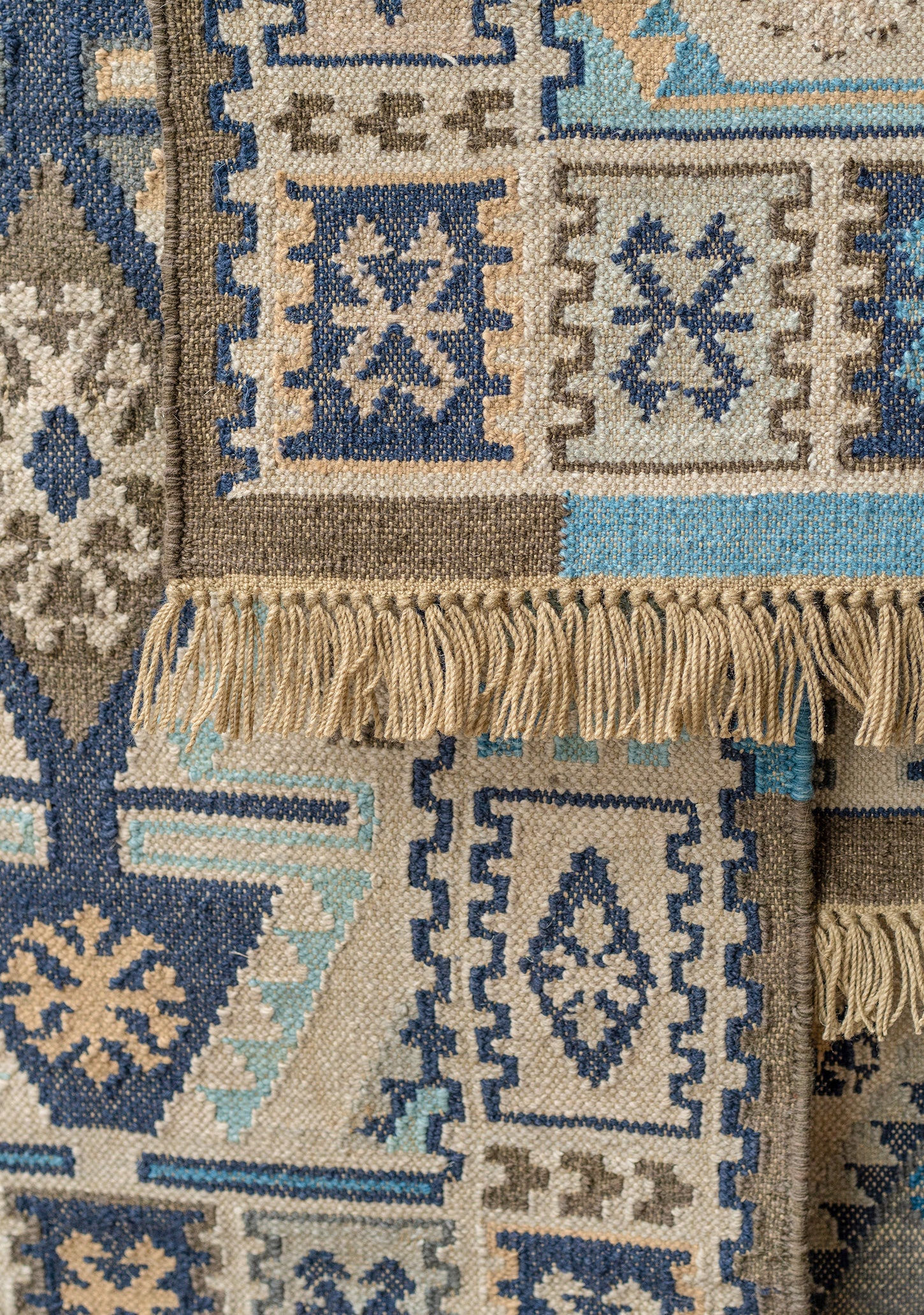 Close-up of a patterned rug with geometric designs in blue, beige, and brown.
