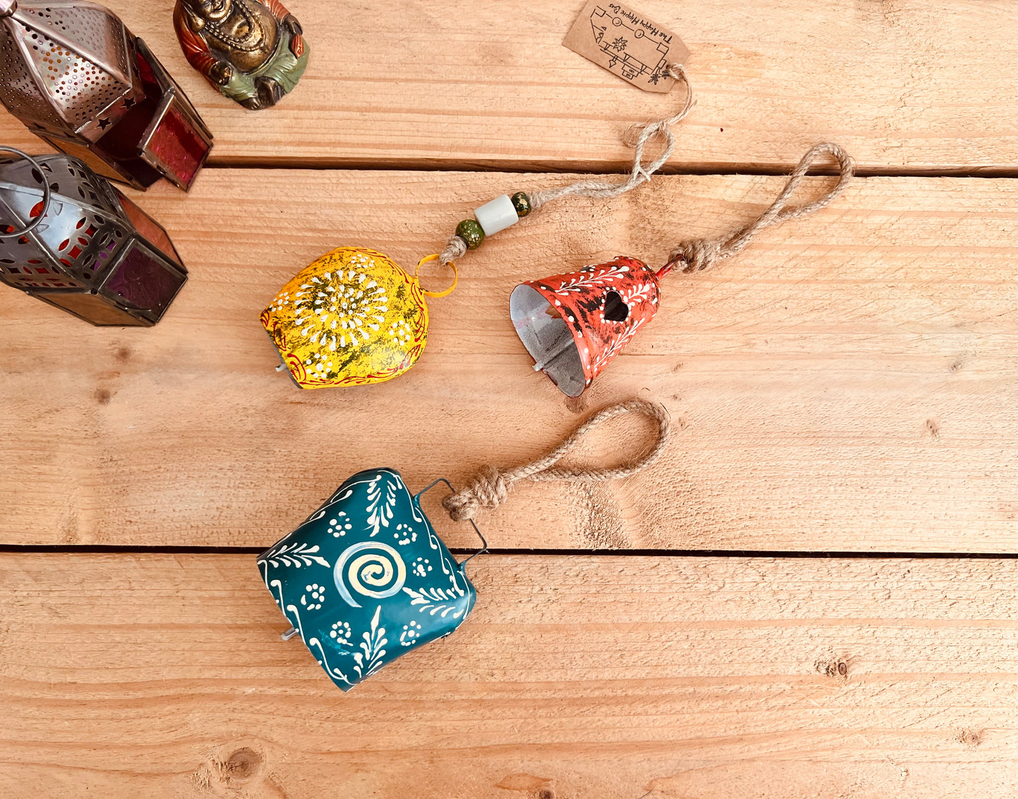 a set of three metal hand painted Indian hanging bells in three different sizes, jute twine hanging cow bell wind chimes in three mixed sizes, yellow, red & blue metal painted bells, handmade, fair trade & ethically sourced hippie boho home decor. 