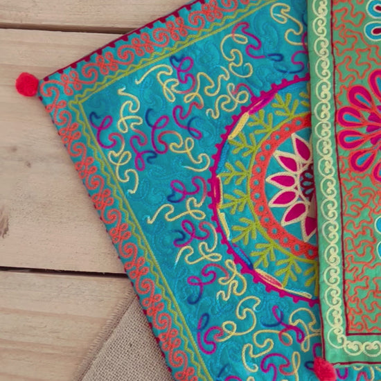vibrant silk style fabric cushion covers with hand embroidered boho hippie chic pattern designs in three vibrant colours with Pom Pom edge detail, handmade fair trade & ethical